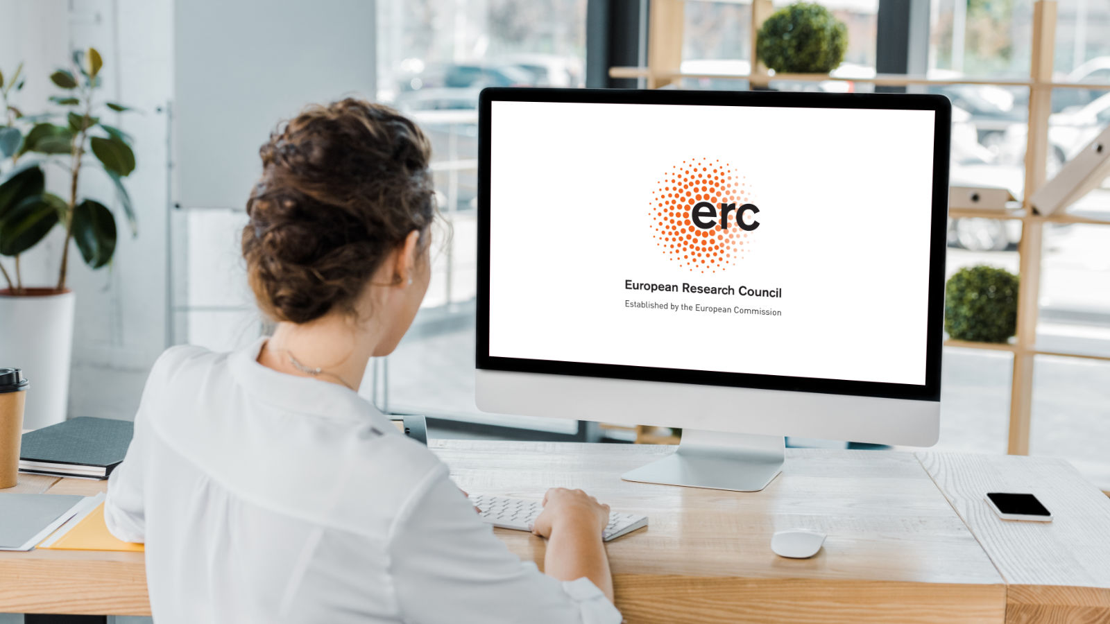 Vista traseira de empresária a trabalhar no computador com gráfico no escritório.