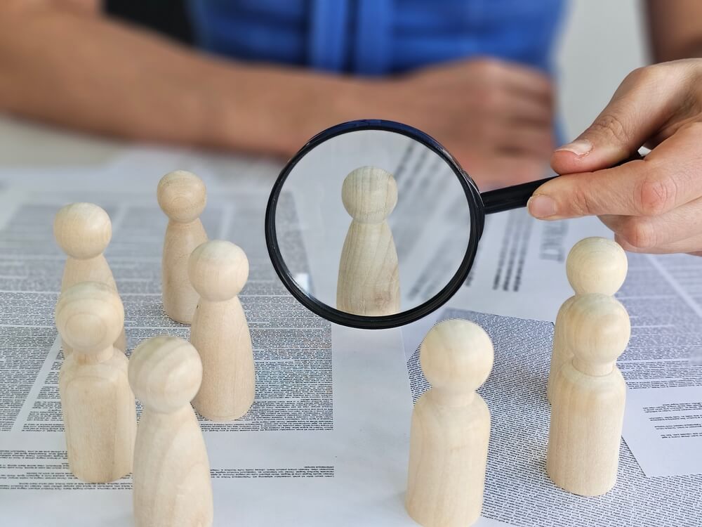 Lupa sobre peões de madeira que representam pessoas