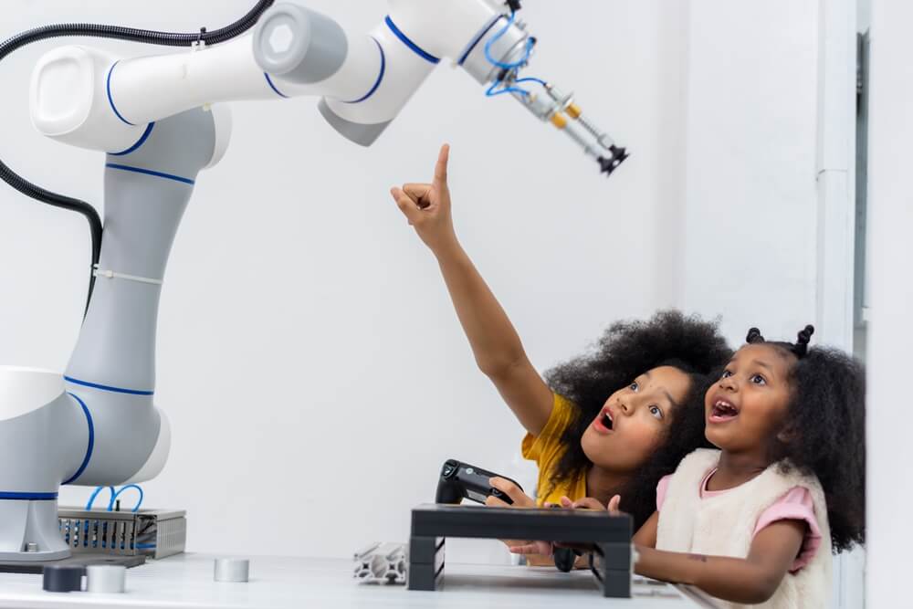 Duas crianças a movimentar braço robóticos e a aprender machine learning.
