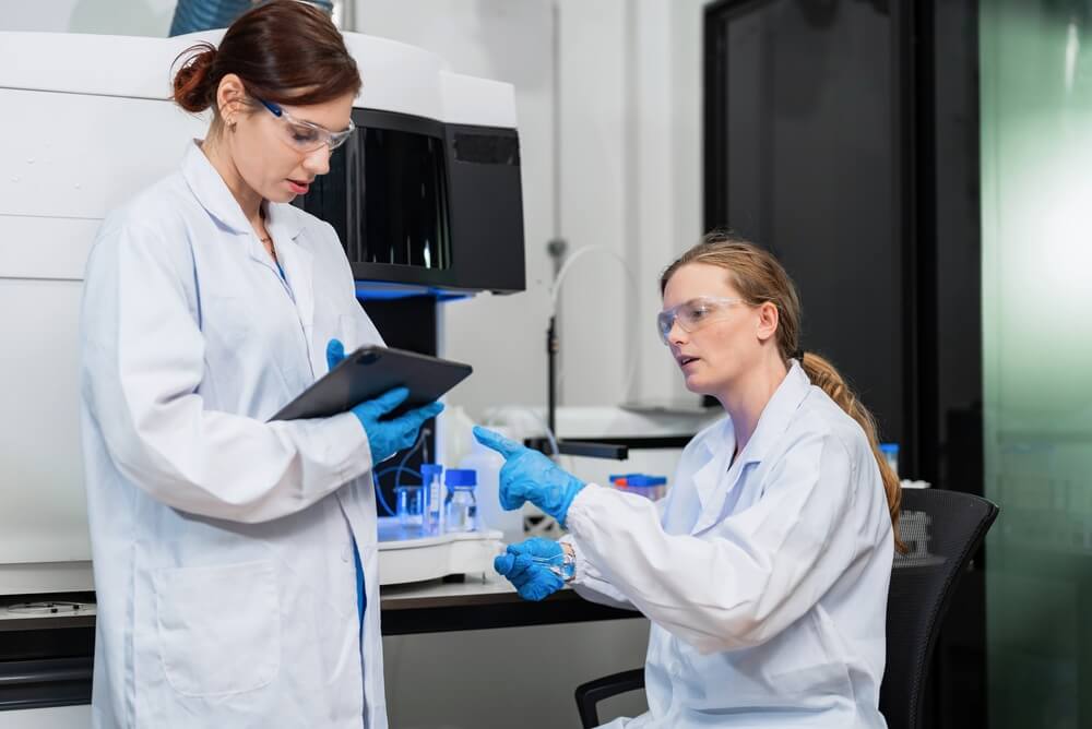 Researchers in a laboratory setting interpreting data on a tablet